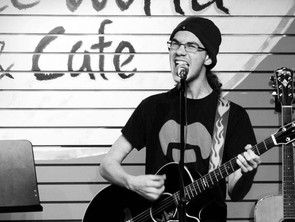 Teenage boy in beanie singing and playing guitar