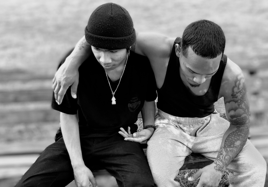 Two young men in park with arms around each other